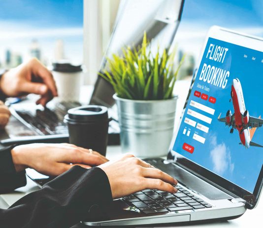 A person using a laptop, on the laptop screen there's plan and seems to be online platform for travel booking